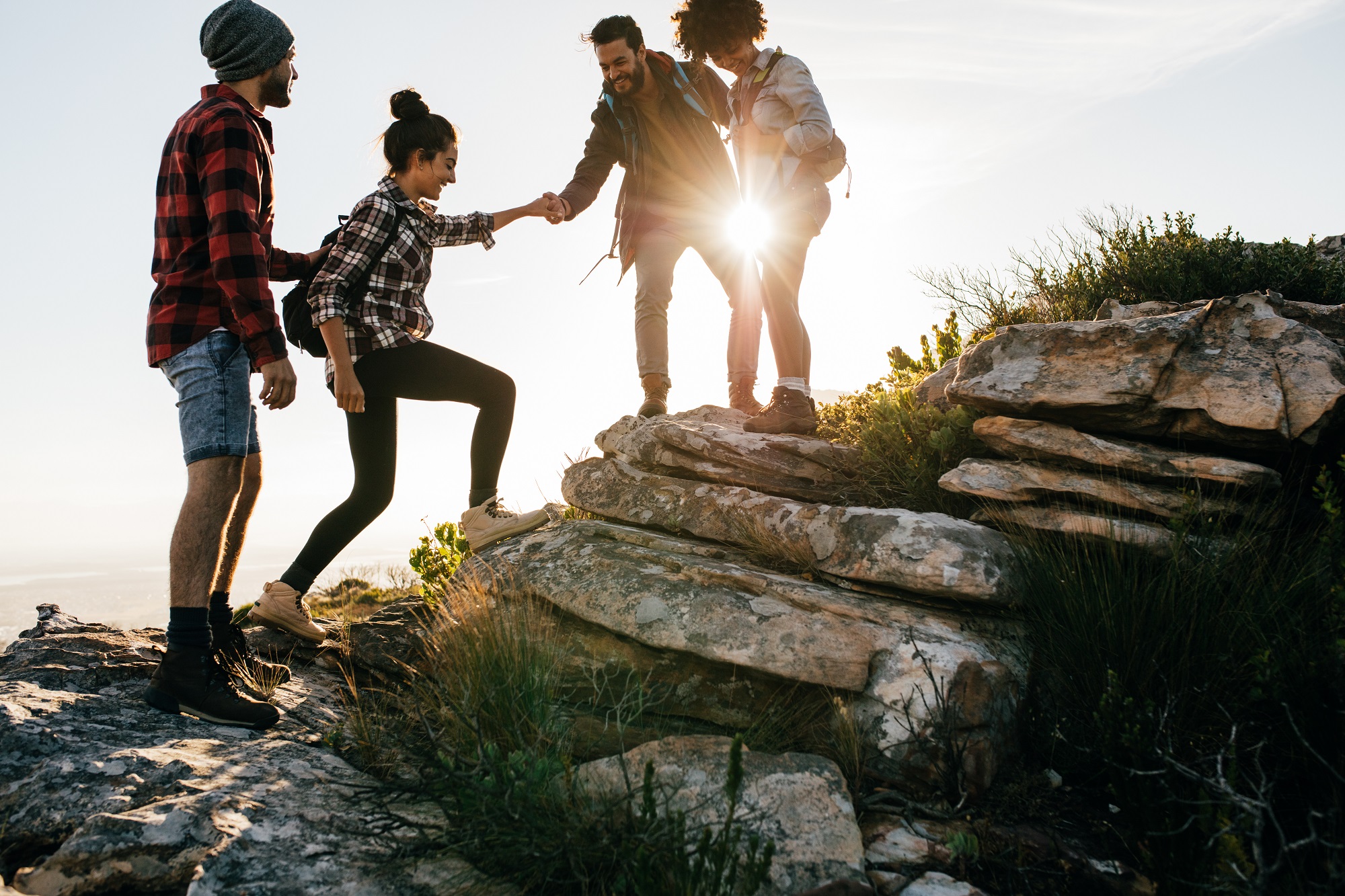 Group of friends hiking in mountain, four hikers walking on a mountain at sunset