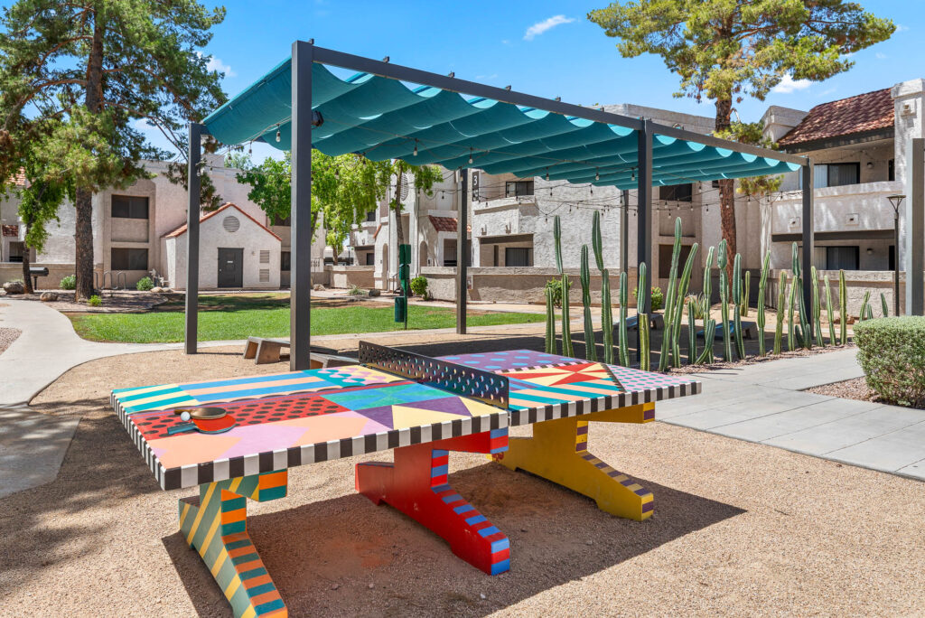 outdoor covered space with cornhole games and a table tennis court