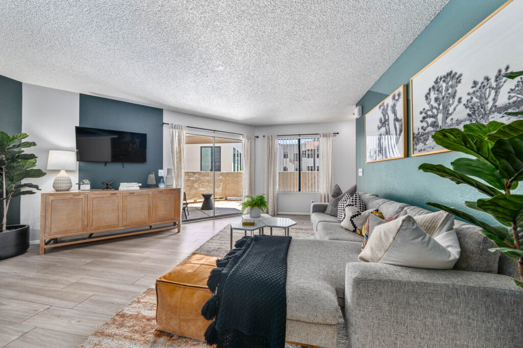 Living room with couch seating, wood-style flooring, TV, accent walls, and natural lighting