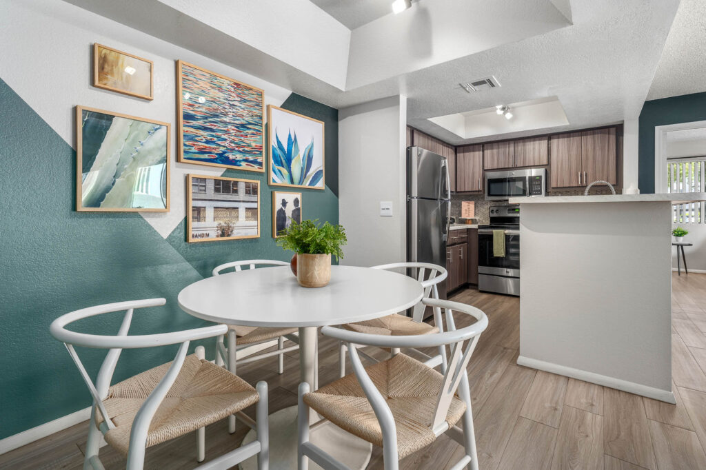 Dining room with wood-style flooring, accent walls, designer lighting, and access to kitchen