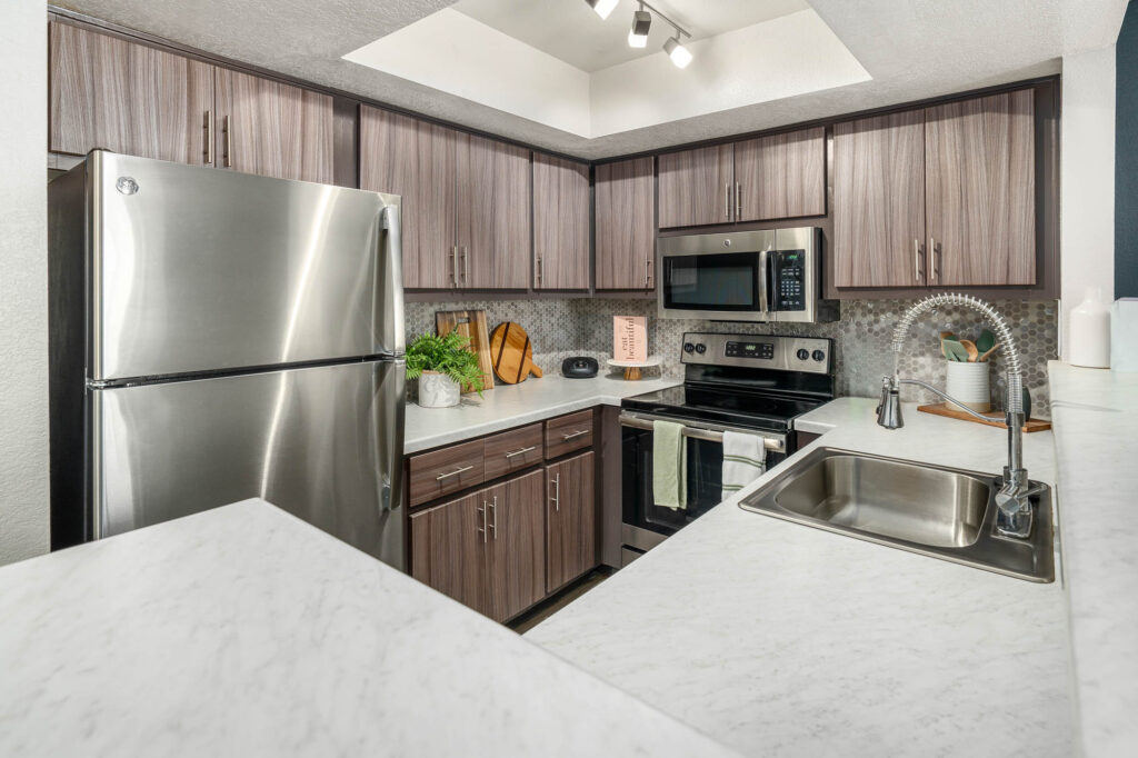 Kitchen with designer lighting, stainless steel appliances, wood-style cabinets and wood-style flooring