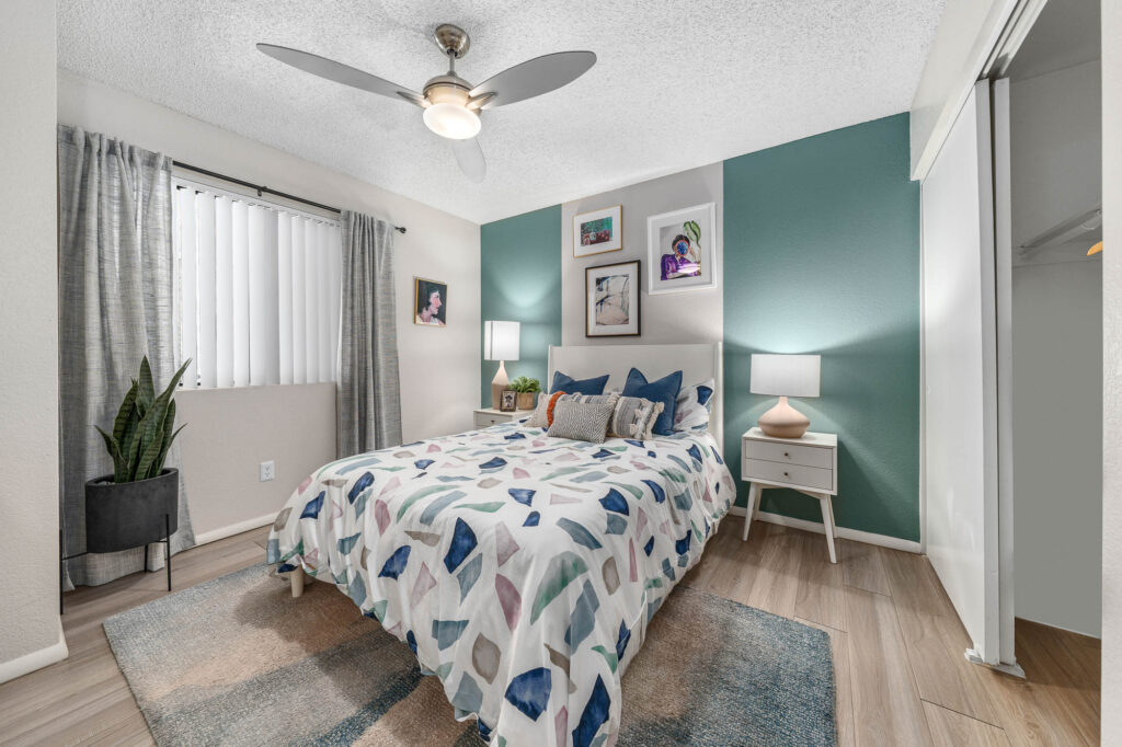 Bedroom with wood-style flooring, lamps, large closet, accent walls, and designer lighting