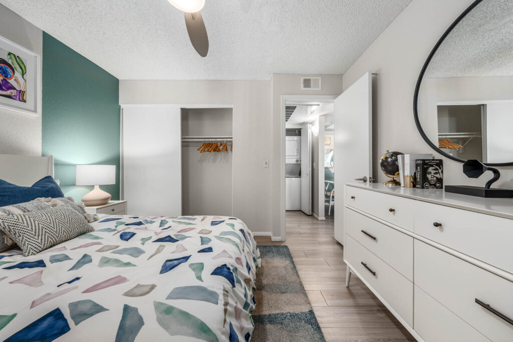 Bedroom with wood-style flooring, lamps, large closet, accent walls, and designer lighting