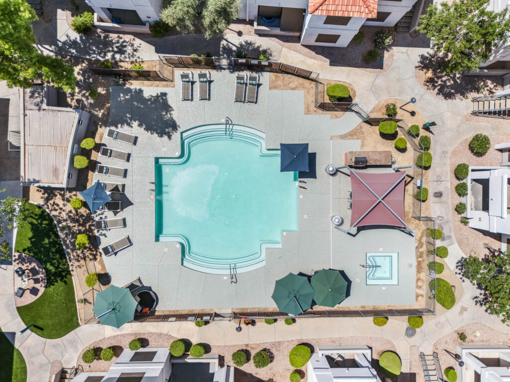 aerial view of swimming pool and hot tub with lounge seating and covered grilling station