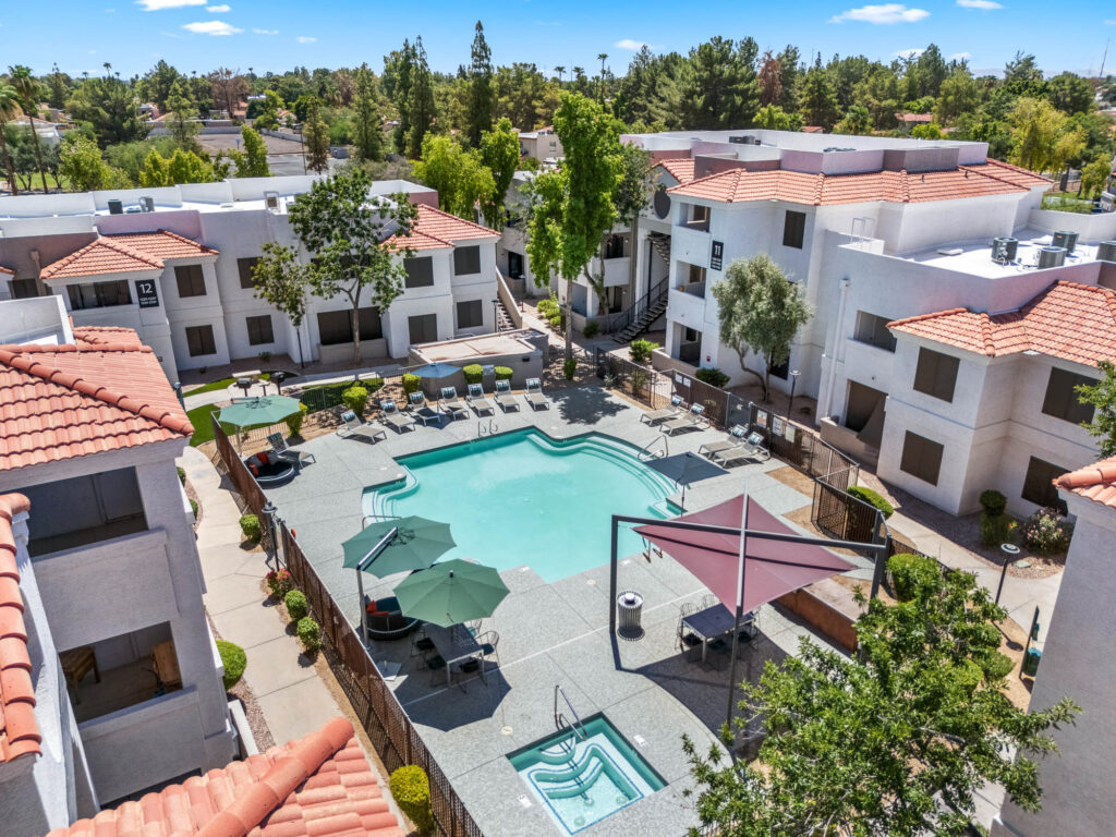Aerial view of swimming pool, outdoor deck, and apartment complex