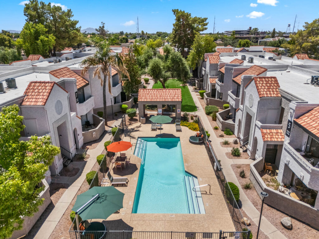 Aerial view of swimming pool, outdoor deck, and apartment complex